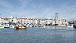 Un port avec des bateaux, une tour imposante et des bâtiments le long de la rive.