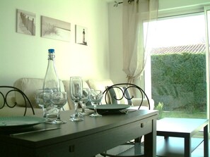 Una mesa de comedor con cristalería y platos, una botella y una silla.