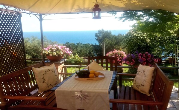 Un área de estar al aire libre con mesa, sillas y vista al mar.
