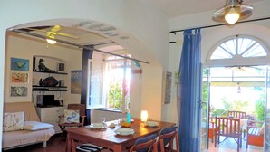 Un comedor con una mesa de madera, sillas y vista al jardín a través de un ventanal.