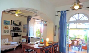 A dining area with a wooden table, chairs, and a view of the garden through a glass door.