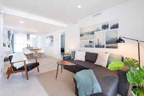 A modern living room with a sofa, chairs, a coffee table, and artwork on the wall.