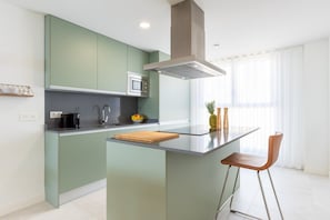 A modern kitchen with a central island, a microwave, and a stainless steel range hood.