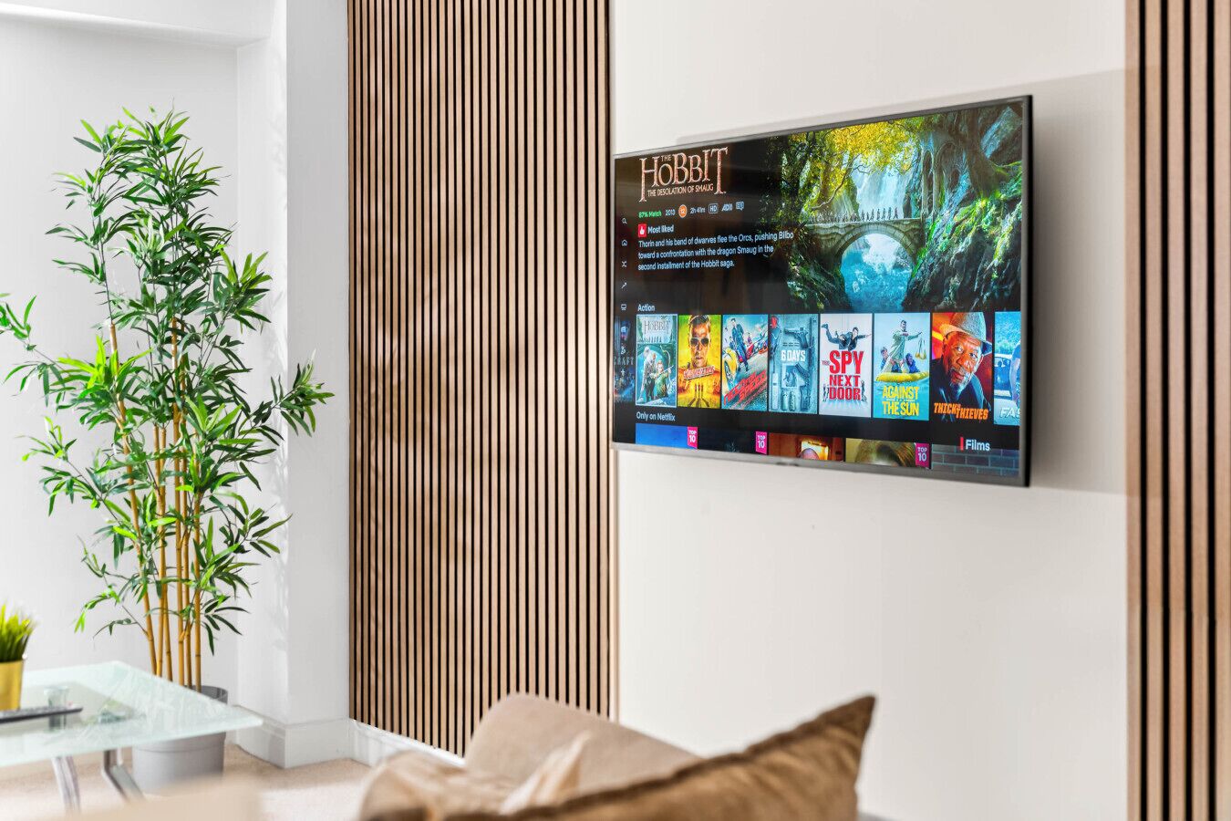 Un salon moderne avec un téléviseur fixé au mur qui affiche une sélection de films.