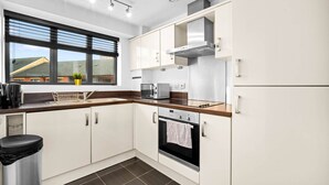 Une cuisine moderne avec des armoires blanches, une hotte de cuisinière en acier inoxydable, un four à micro-ondes et une cuisinière.