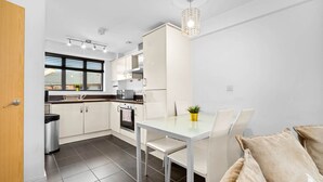 Une cuisine moderne avec des meubles blancs, une table à manger et un lustre.
