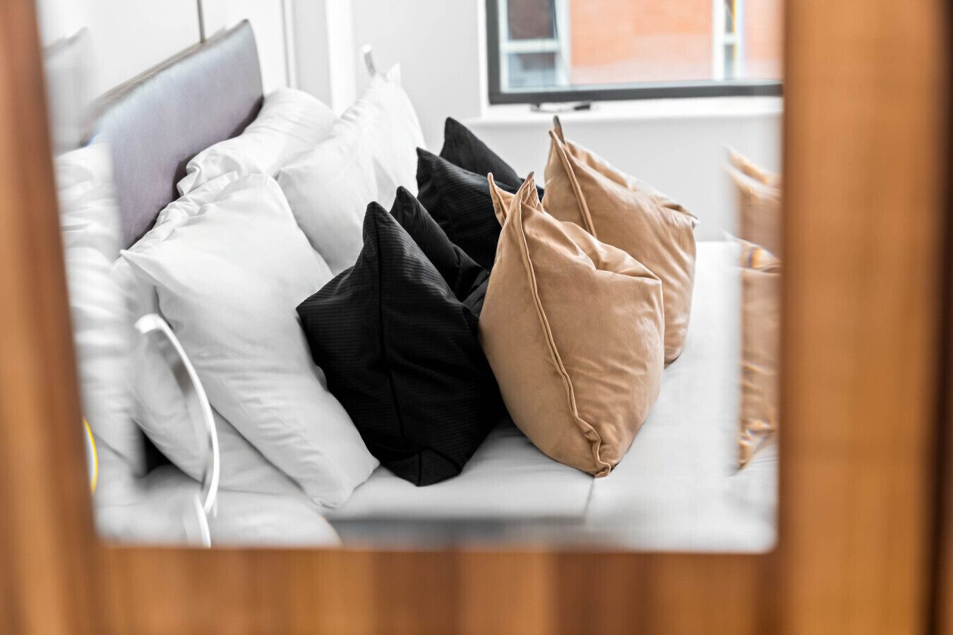 Ein Bett mit weißen, schwarzen und beigen Kissen.