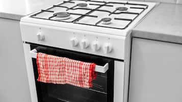 A white stove with four burners and a single oven door.