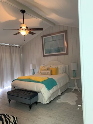 Relax in this inviting bedroom with a large bed, ceiling fan, and framed picture.
