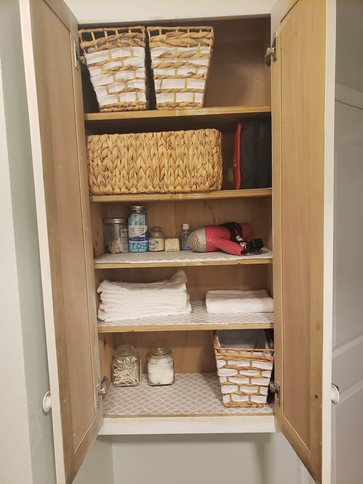 A wooden wardrobe with multiple shelves, baskets, and storage containers.