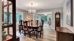 A dining area with a chandelier, wooden chairs, and a dining table. - Easy Beach Living – Single-Story Coastal Retreat - 5-Minute Walk to the Beach (Hilton Head Island)