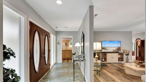 A modern living room with a large flat-screen TV, a glass coffee table, and a wooden floor. - Easy Beach Living – Single-Story Coastal Retreat - 5-Minute Walk to the Beach (Hilton Head Island)