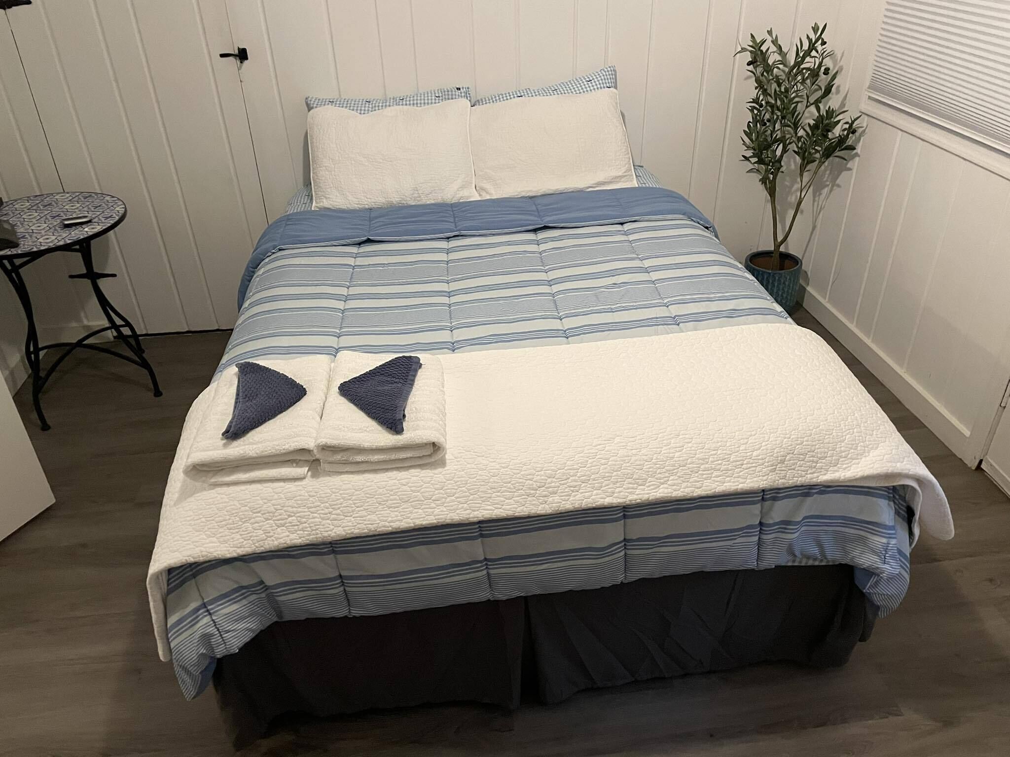 A neatly made bed with a striped bedspread, two pillows, and folded towels.