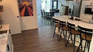 Una cocina moderna con barra, suelo de madera y zona de comedor con sillas.