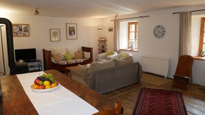 A cozy living room with a wooden dining table, a sofa, a TV, and a radiator. - Exceptional and spacious apartment – Coup de Cœur – in the heart of the resort (Vars)