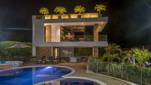 A modern two-story building with a pool, outdoor seating, and palm trees. - Chalet La Alemania (Calarcá)