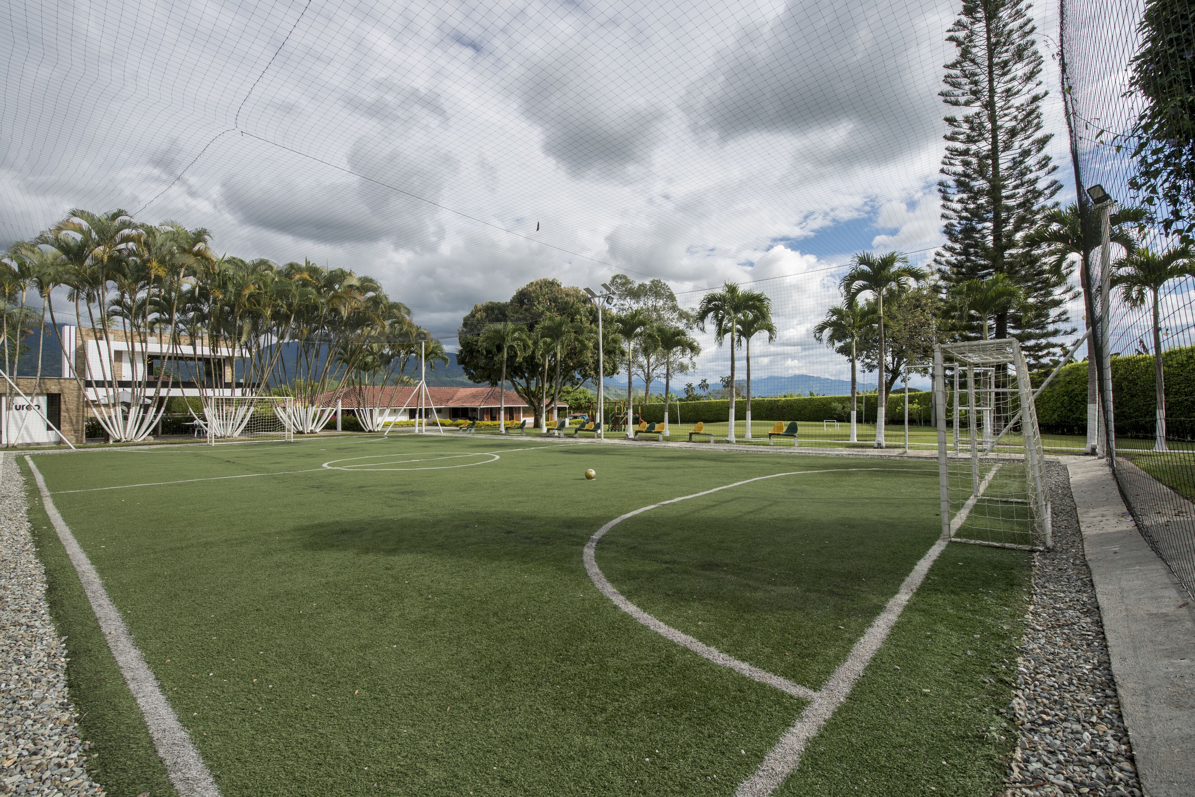 A soccer field with goalposts, surrounded by trees and a building in the background.