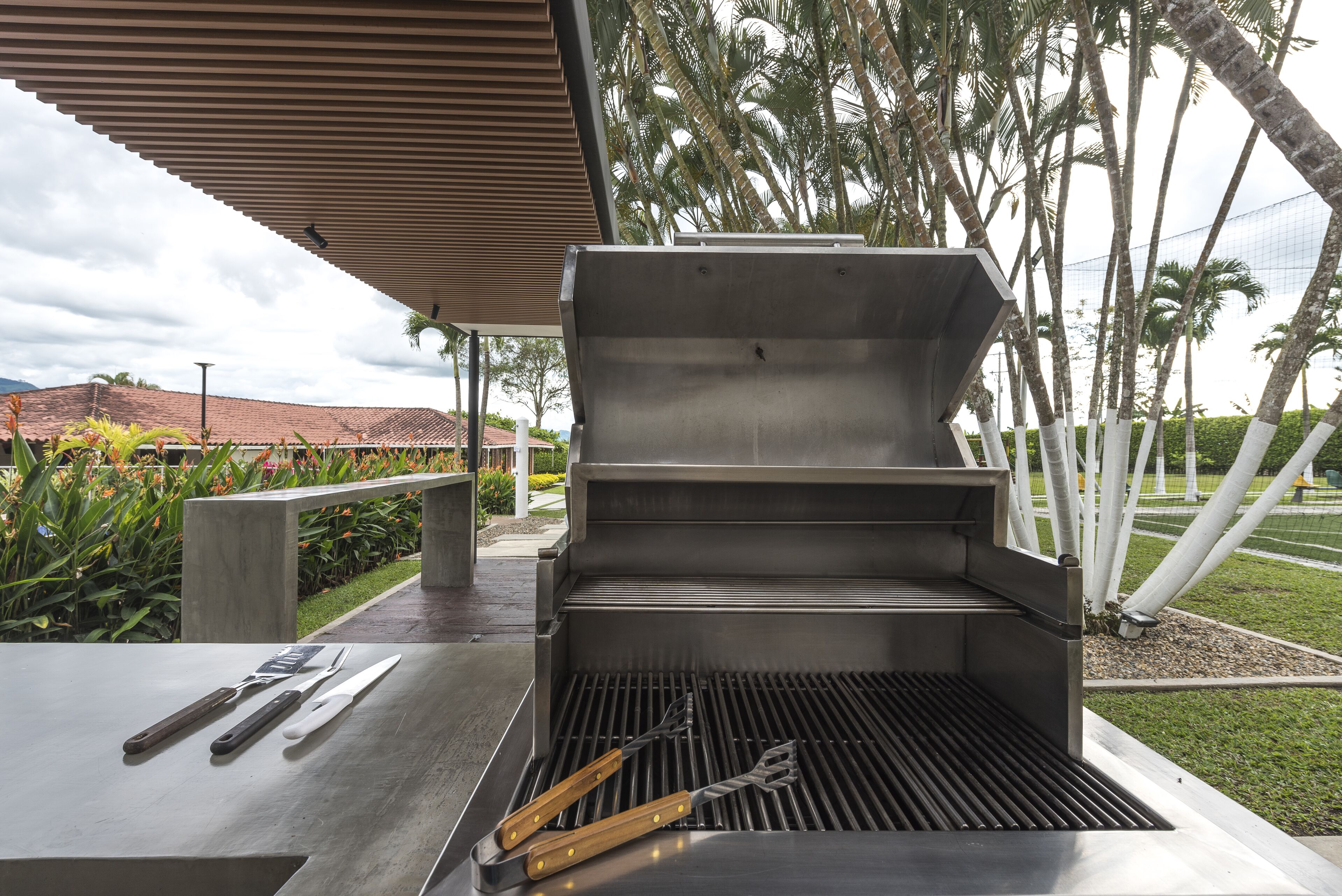 Un espace barbecue extérieur moderne, doté d’un banc et d’ustensiles de cuisson.