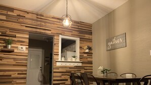 Un coin repas avec un mur en bois, un luminaire suspendu et un panneau mural portant l’inscription « Gather ».