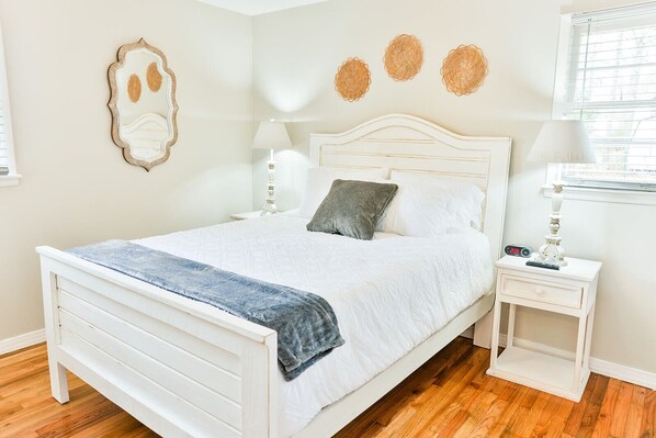 A neatly arranged bedroom with a bed, bedside tables, and decorative wall art.