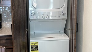 Un appareil compact, combinant lave-linge et sèche-linge, avec un panneau de commande et un autocollant indiquant son niveau d’efficacité énergétique.