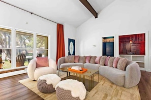 A modern living room with a sectional sofa, a coffee table, and a large window with curtains.