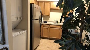 A compact kitchen with wooden cabinets, a stainless steel refrigerator, and a tiled floor. - Villa-style condo with pool on the beach - Condo 1 (Holmes Beach)