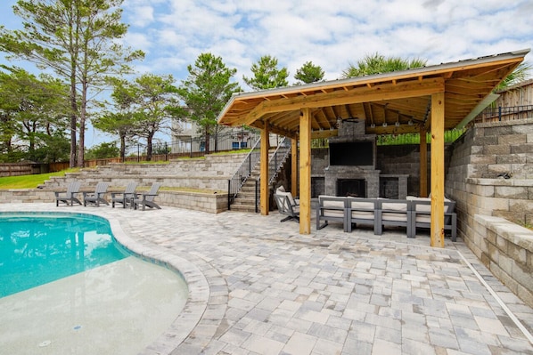 Un jardin avec une piscine, un espace barbecue et un mur en pierre.
