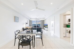 A modern living room with a dining area, a sofa, a TV, and a ceiling fan.
