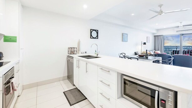 Een moderne keuken met witte kastjes, een inbouwoven en een groot eiland met een spoelbak.