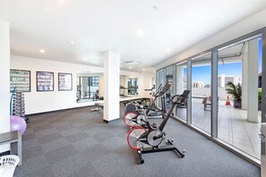 Une salle de sport moderne équipée de machines de cardio, dotée d’une grande fenêtre et offrant une vue sur la ville.