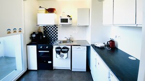 A compact kitchen with white cabinets, a microwave, a coffee machine, a dishwasher, and a checkered backsplash. - Bright, young private room (Saint-Denis)