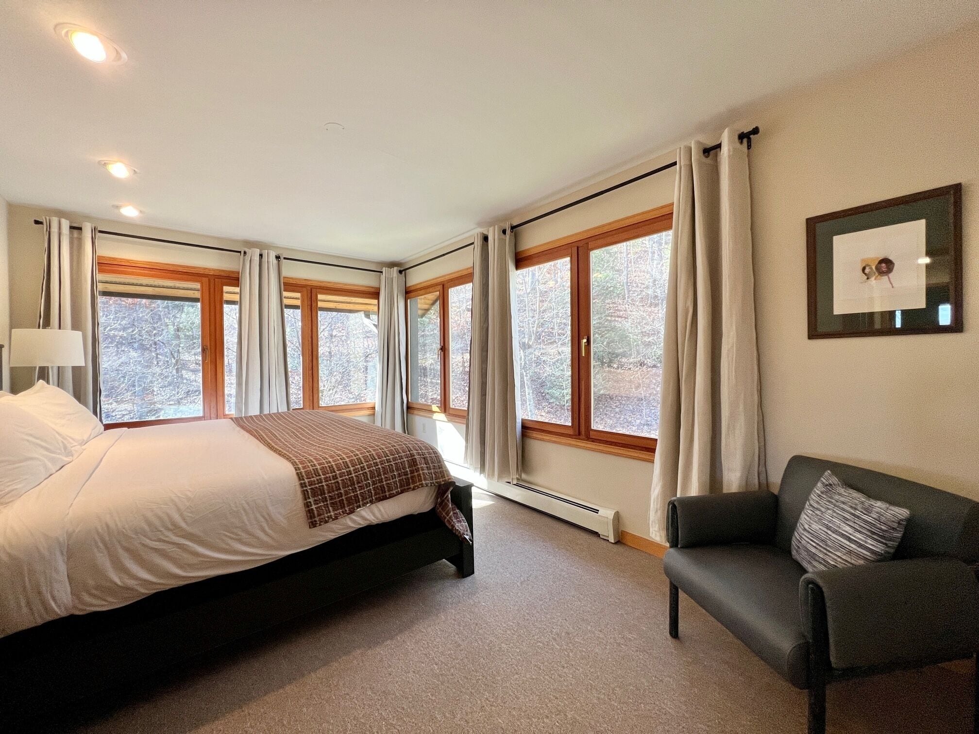 Une chambre à coucher avec un grand lit, une chaise et de nombreuses fenêtres.