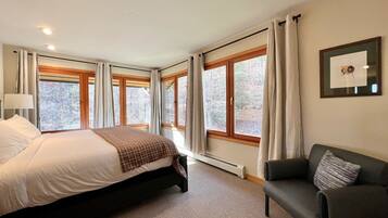 Une chambre à coucher avec un grand lit, une chaise et de nombreuses fenêtres.