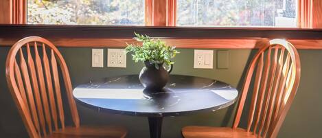 Un comedor con dos sillas de madera, una mesa y una lámpara colgante.
