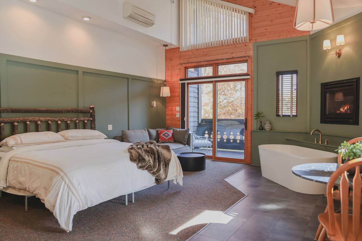 Ein Schlafzimmer mit einem großen Bett, einer Sitzecke mit einer Couch, einer Badewanne und einem Kamin.