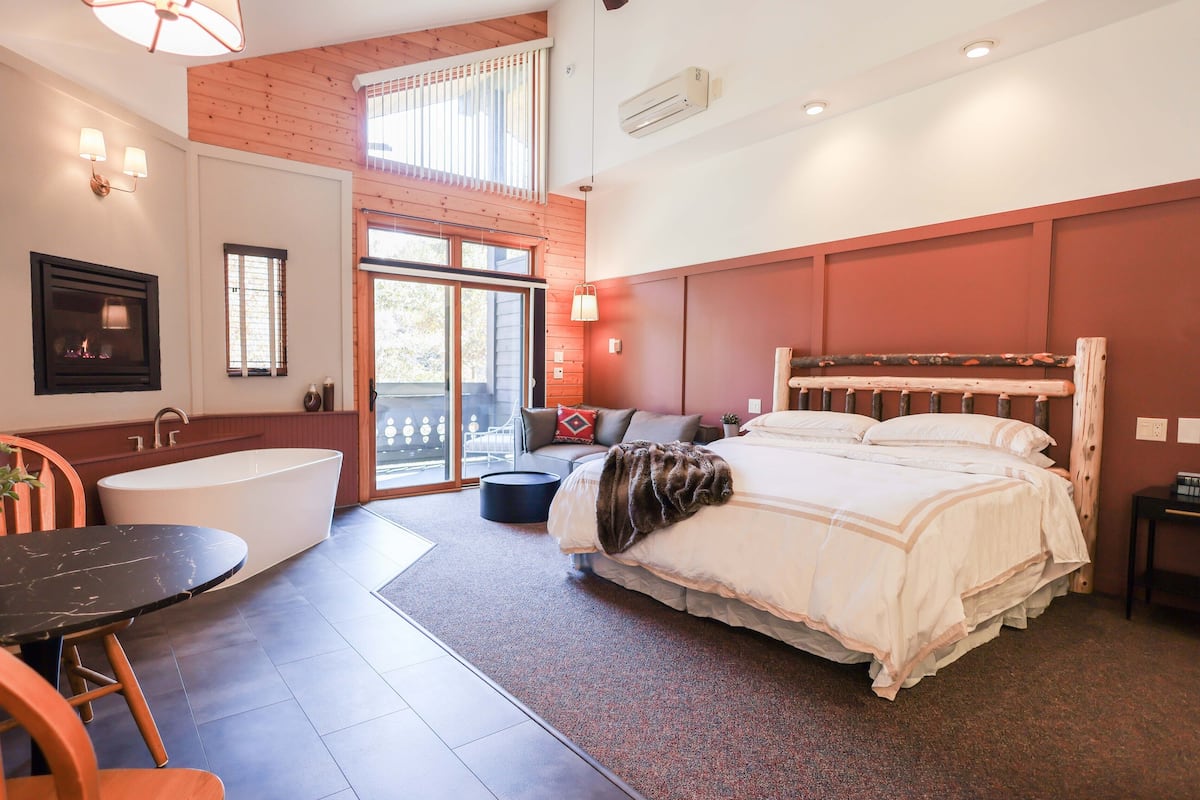 Ein modernes Schlafzimmer mit einem großen Bett, einer Badewanne und einem Essbereich.