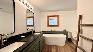 A bathroom with a vanity, a bathtub, and a toilet.