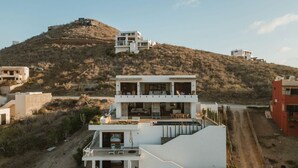 Et moderne hus med to etager, fladt tag, store vinduer og en balkon.