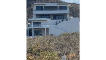 A multi-story building with balconies, situated on a hillside.