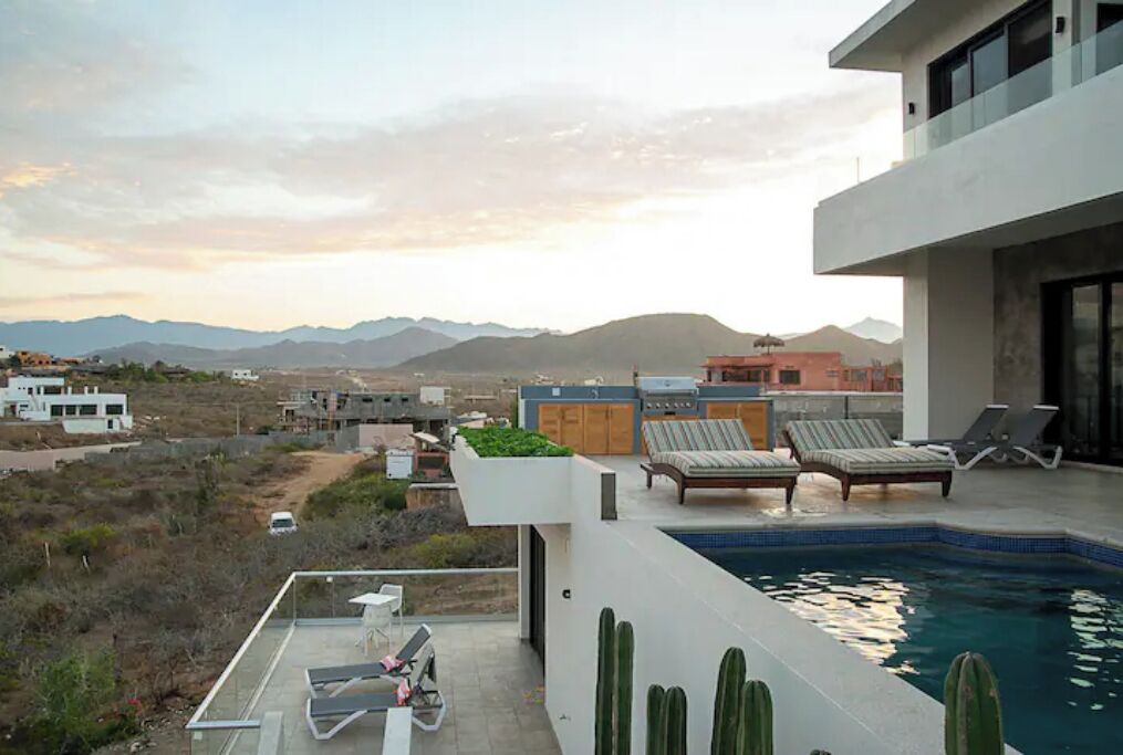 A rooftop pool area with lounge chairs and a view of mountains.
