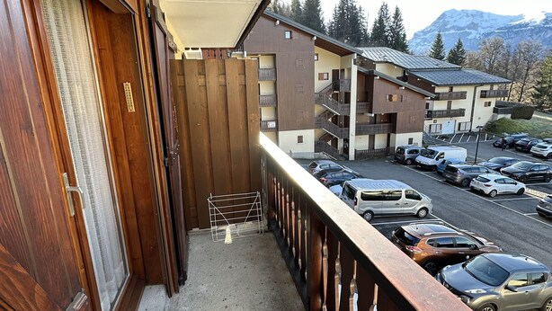 A balcony with a view of a parking lot and buildings in the background.