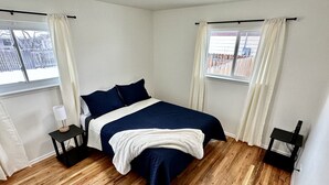 Un dormitorio con cama, dos mesitas de noche, una ventana y vistas a una terraza de madera.