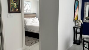 A modern hotel room with a bed, a small table, and a painting on the wall.