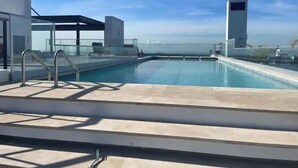 A rooftop swimming pool with clear skies and a view of the horizon.