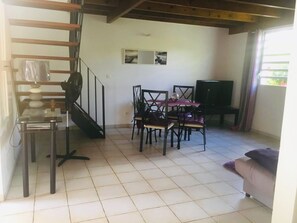 Un salon comprenant un coin repas, un escalier et un téléviseur.
