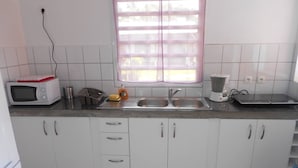 A kitchen with white cabinets, a microwave, a coffee maker, and a toaster. - Gîte Papaye · RESIDENCE LES KALBASSIERS (Lamentin)
