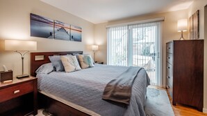 A bedroom with a bed, bedside tables, a nightstand, a window with blinds, and a wall-mounted artwork. - Cozy Home in the Heart of Corvallis (Corvallis)