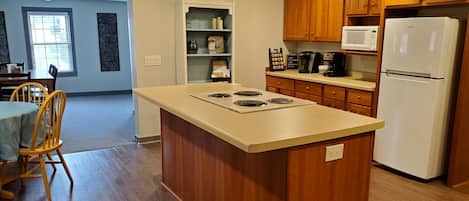 A kitchen with wooden cabinets, a white refrigerator, a built-in oven, and a dining area with a table and chairs.