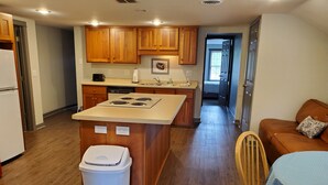 A modern kitchen with wooden cabinets, a central island, and a dining area with a table and chairs.